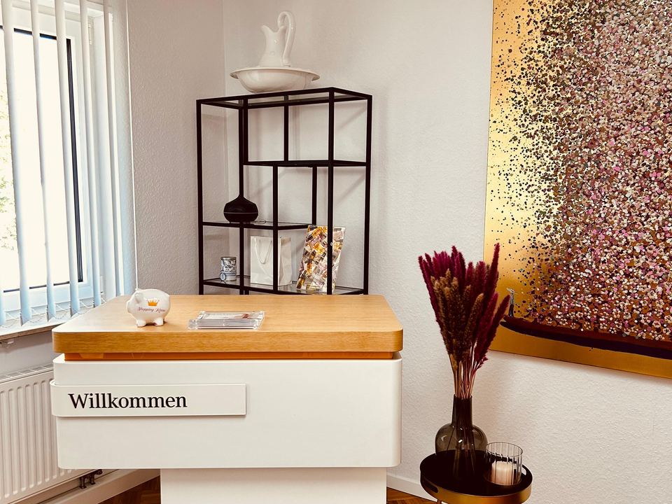 Empfangstheke mit Willkommen-Schild, Regal und Kunstbild