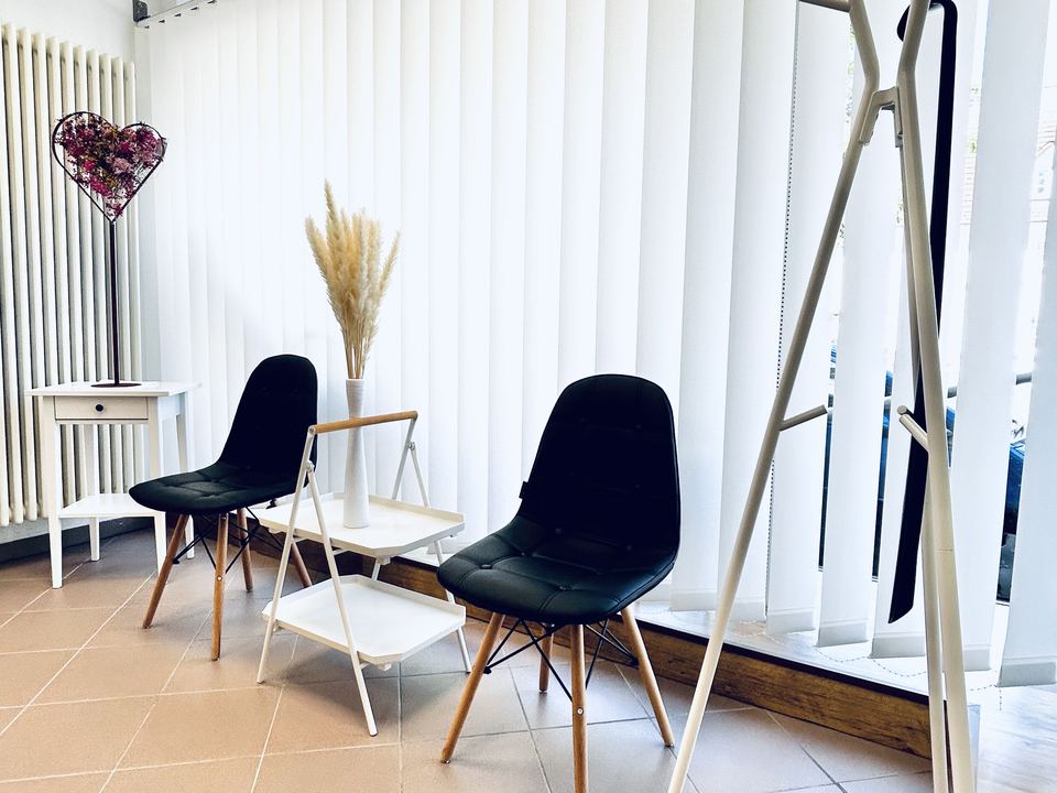 Heller Wartebereich mit zwei Stühlen, Trockenblumen und Garderobe